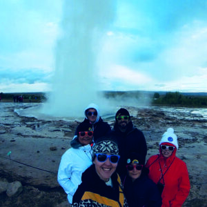 A group of humans watching the geyser erupt at Geysir geothermal area in Iceland